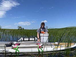 Christine Cornish standing in a wetland with all of her equipment